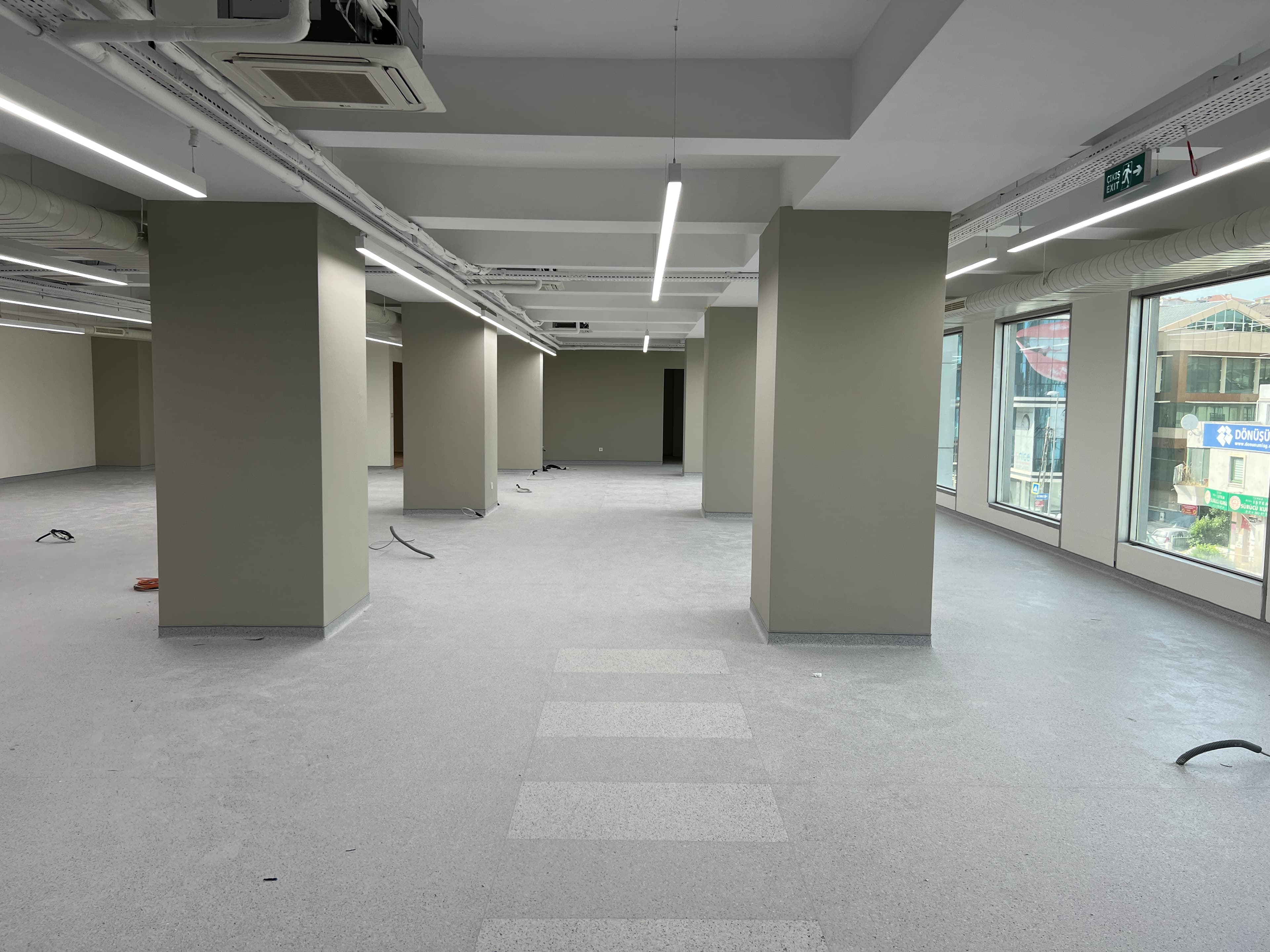 Open floor with painted columns and carpet tile patches being laid